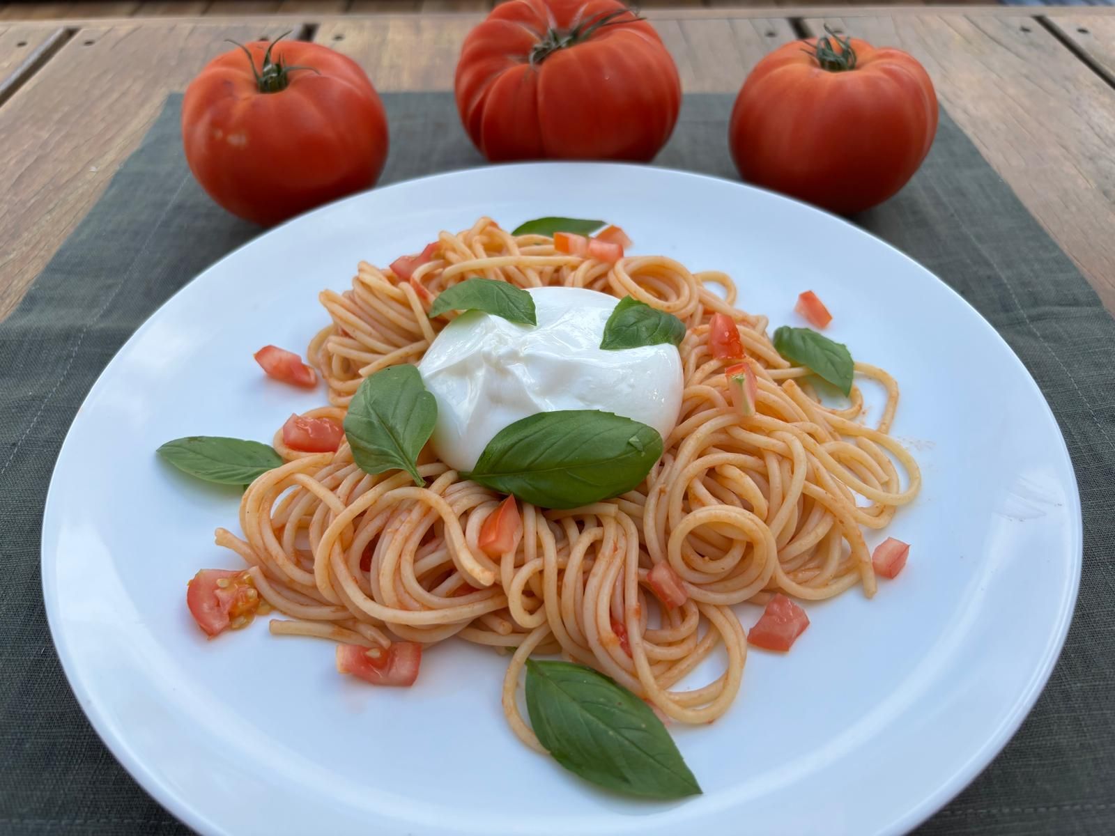 Spaghetti with burrata and tomatoes topped with fresh basil