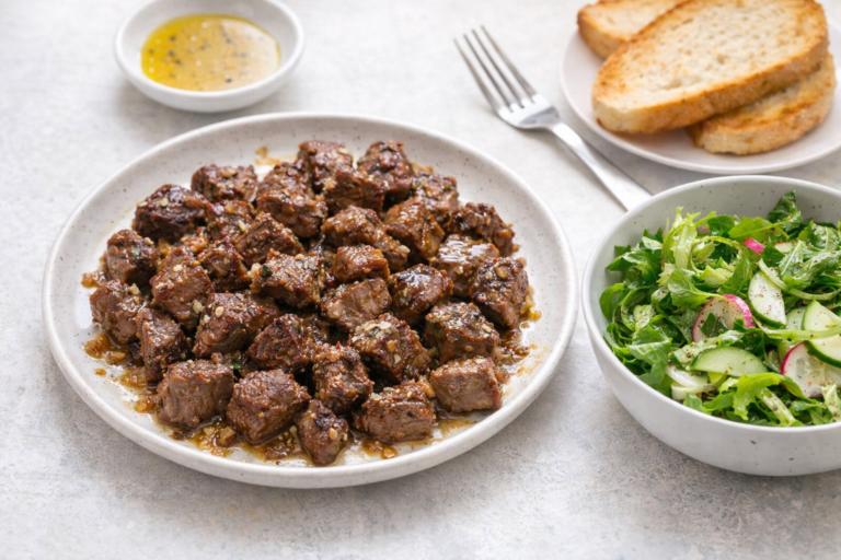 Butter-finished steak with salad and toast on a simple table.