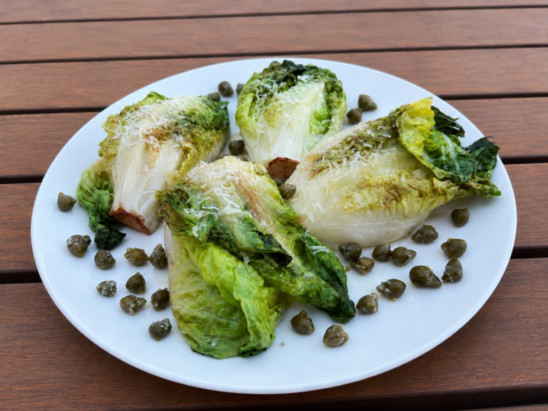 Grilled romaine hearts topped with Parmesan, lemon, capers and extra virgin olive oil, served as an elegant grilled side dish.