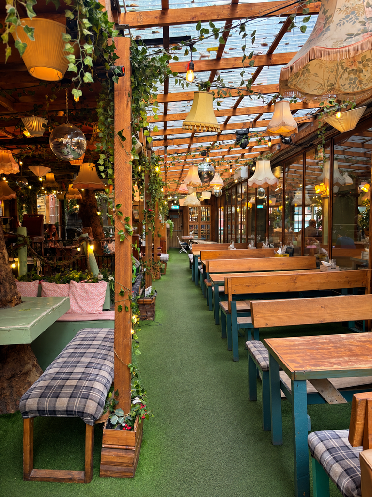 Zelený interiér Mala v Manchestri s vintage lampami a rastlinami