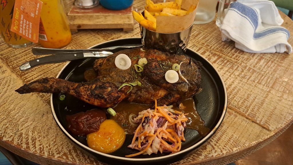 Caribbean jerk chicken with fries, coleslaw and BBQ sauces